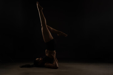 Fit Women Performing Yoga Postures Depicting Fitness in dull light and black background wearing black sports wear 