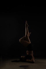 Fit Women Performing Yoga Postures Depicting Fitness in dull light and black background wearing black sports wear 