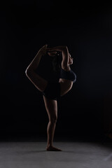 Fit Women Performing Yoga Postures Depicting Fitness in dull light and black background wearing black sports wear 