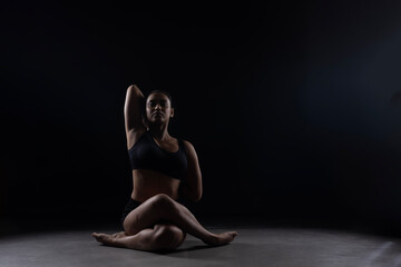 Fit Women Performing Yoga Postures Depicting Fitness in dull light and black background wearing black sports wear 