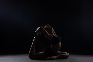 Fit Women Performing Yoga Postures Depicting Fitness in dull light and black background wearing black sports wear 