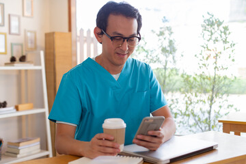 Smiling nurse using digital tablet in employee lounge. Male nurse takes a break outside of a coffee shop.