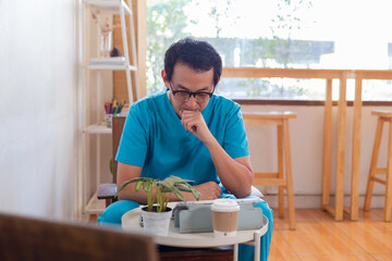 Smiling nurse using digital tablet in employee lounge. Happy nurse resting on couch in lounge area and drinking cup of coffee.