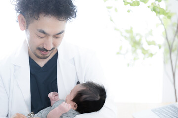 赤ちゃんを抱っこして診察する医師