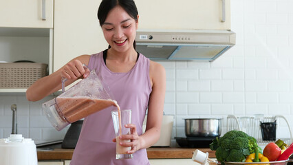 Asian woman preparing vegetables fruit blended drink for skin and health after exercising for...