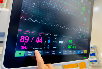Hospital monitor displaying vital signs: heart rate, blood pressure, oxygenation, temperature, and...