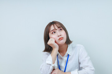 	頬杖をつき天井を見上げる若い女性スタッフ