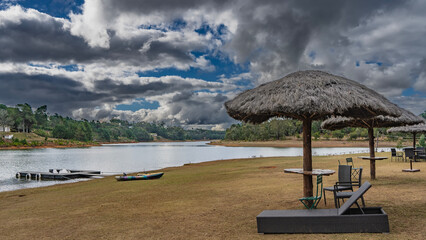 Recreation area on the lake shore. Sun beds, straw sun umbrellas stand in a row. A bright canoe, a...