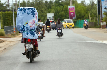A motorcyclist carries a high load wrapped in textiles, Bangkok, Thailand