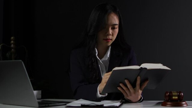 Female lawyer working on legal documents on the desk reading contract agreement documents.