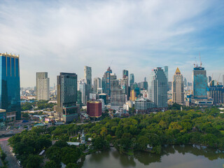 Fototapeta na wymiar Aerial view of Lumphini Park backgrounded by the Silom area skyline office building business district
