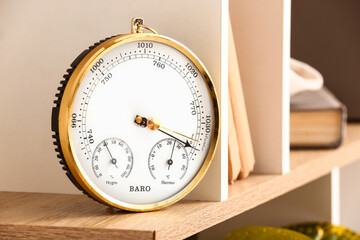 Aneroid barometer and books on shelf, closeup
