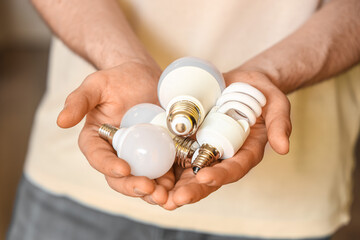 Man holding different light bulbs at home, closeup
