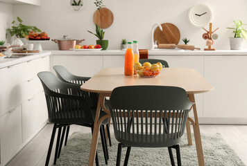 Wooden dining table with orange juice and fresh fruits in modern kitchen