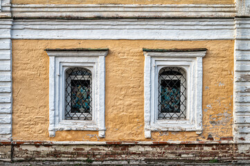 Fototapeta na wymiar Facade of ancient building with windows with lattice. Textured Background.