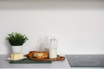 Board with croissants, milk and butter on white kitchen counter