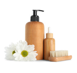 Bottles of cosmetic products, massage brush and chamomile flowers on white background