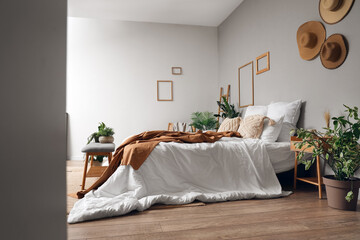 Interior of cozy bedroom with comfortable bed and grey bench, view through hallway