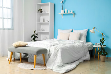 Interior of cozy bedroom with comfortable bed and grey bench