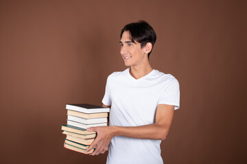 Funny student posing with books in studio on brown background.