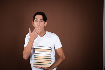 Funny student posing with books in studio on brown background.