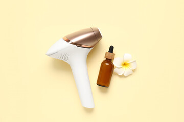 Modern photoepilator with cosmetic oil and beautiful flower on pale yellow background