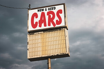 Old worn new and used cars sign at auto dealership