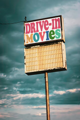Old worn vintage drive-in movies sign with cloudy sky