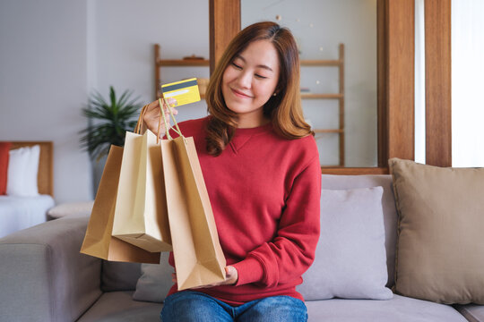 Portrait image of a woman with shopping bags holding and showing a credit card for purchasing