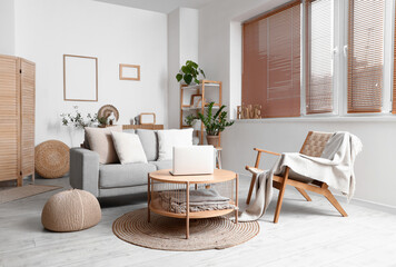 Fototapeta premium Interior of modern living room with grey sofa and laptop on wooden coffee table