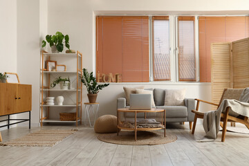 Interior of modern living room with grey sofa, armchair and laptop on coffee table