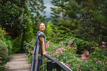 Young woman traveler enjoying with blooming flowers garden flowers farm Travel lifestyle concept. A beautiful Refreshed woman in the Graden.