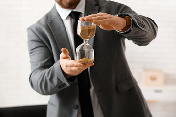 Young businessman with hourglass in office. Time management concept