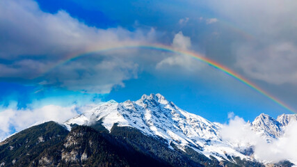 The mountain view of alpine as snow-capped mount peaks  with rainbow scene in Winter mountains scene