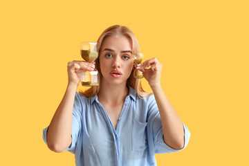 Young businesswoman with hourglasses on yellow background. Time management concept