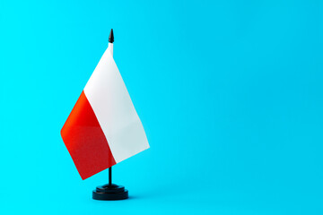 Small flag of Poland on flagpole on blue background