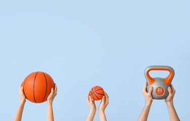 Female hands with balls for playing basketball and kettlebell on blue background