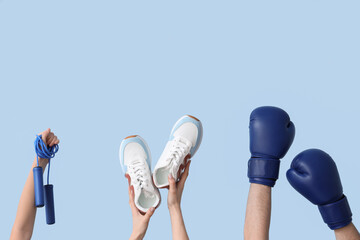 Female hands with skipping rope, sneakers and boxing gloves on blue background