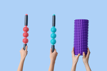 Female hands with foam and body rollers on blue background