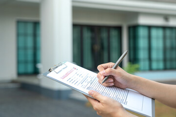 Foreman's hand is using a pen checking on building inspection report form to QC building quality of...