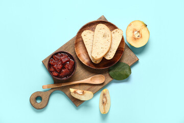 Board with sweet jam, bread pieces and quince fruits on blue background