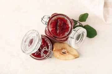 Jars of sweet jam with quince fruits on white table, closeup