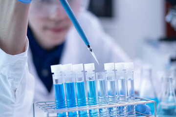 Professional scientist chemist technician analysis research experiment virus blue liquid pipette glass test tube equipment in hospital laboratory, woman doctor white lab coat medical research develop