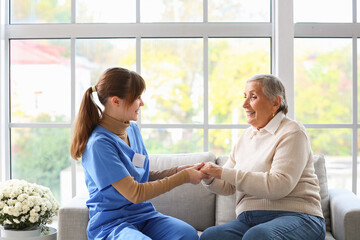 Senior woman with caregiver holding hands at home