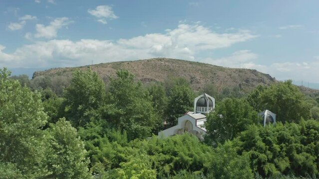 Descending pedestal aerial drone shot of St. Petka church and the Kozhuh mountain located in the town of Rupite,Petrich, Bulgaria.