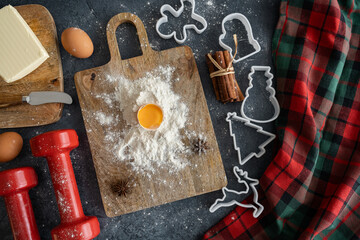 Healthy fitness Christmas baking flat lay. Dumbbells, eggs, cookie cutters. Fit diet food preparation. Gym workout, sport training composition. Winter Holiday season indulgence, stay in shape concept.