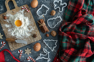 Christmas cookies baking composition on a flour-dusted kitchen table. Fresh eggs dough ingredients,...