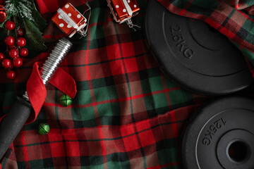 Dumbbell barbell weight plates, Christmas decorations on tartan plaid. Healthy fitness Holiday season composition. Gym workout, sport training flat lay with copy space. Exercise equipment as gift idea