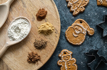 Christmas baking composition, with gingerbread cookies, flour, spices and cookie cutters. Holiday Season winter flat lay background. Seasonal baking ingredients top view.