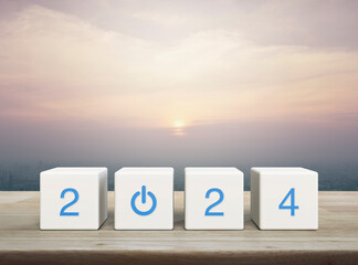 2024 start up business icon on white block cubes on wooden table over modern city tower and...